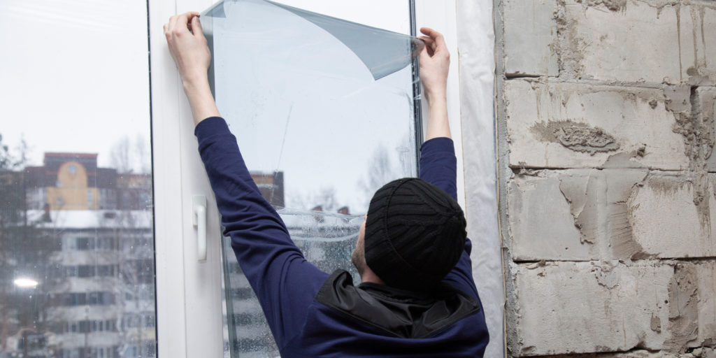 A man applying exterior window film to a glass door.